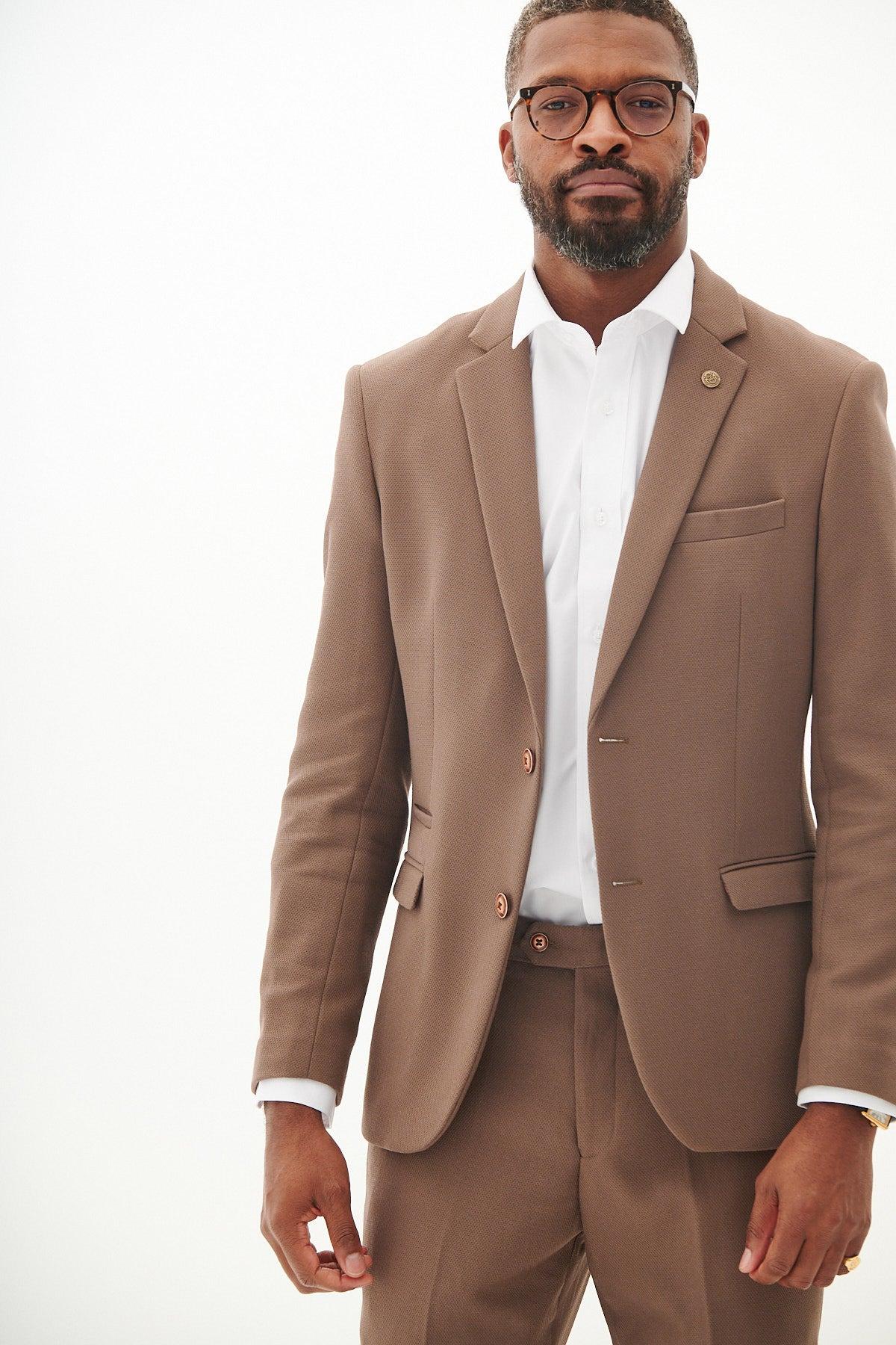 A man models the marcdarcy HM5 - Tan Tailored Blazer with paisley lining, paired with glasses and a white dress shirt, standing against a plain white background and looking at the camera.