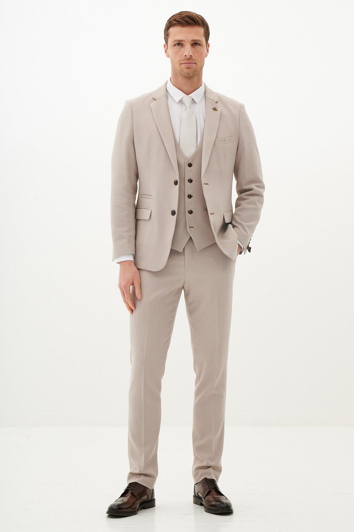 A man with short brown hair models the Marc Darcy HM5 - Stone Tailored Three Piece Suit, paired with a white shirt, light tie, and dark brown shoes against a white background—a great inspiration for a Harry Maguire wedding look.