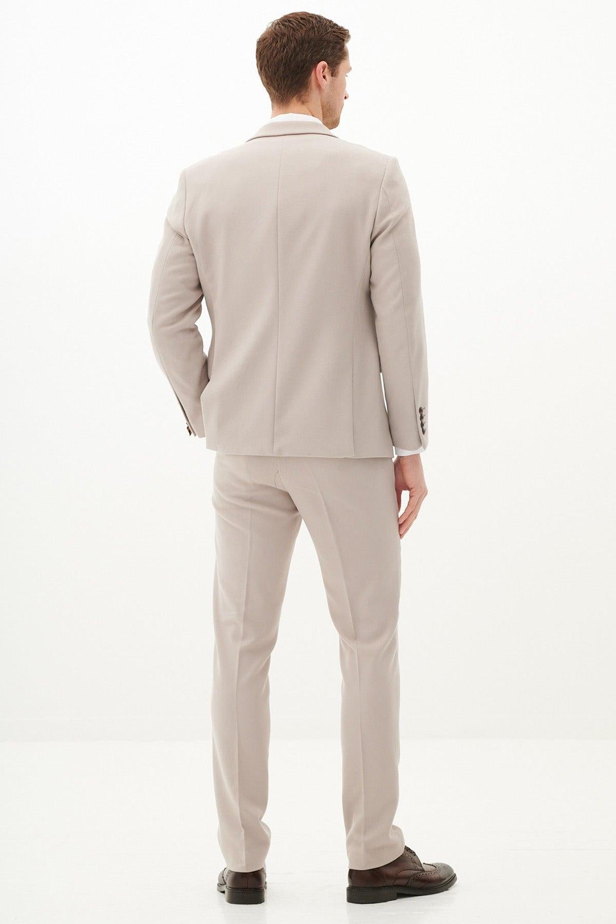 A man faces away, wearing the Marc Darcy HM5 - Stone Tailored Two Piece Suit in slim fit with matching pants and dark brown shoes, set against a plain white background.