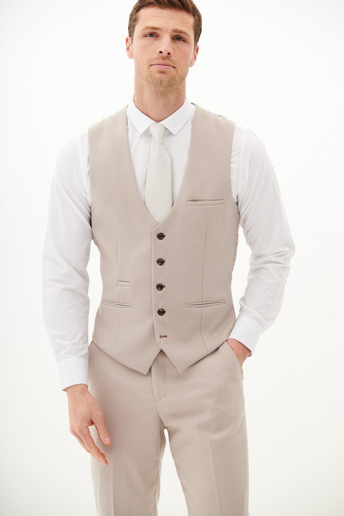 A man models the Marc Darcy HM5 - Stone Tailored Three Piece Suit, featuring a light beige vest and pants, white dress shirt, and light-colored tie against a plain white background, facing the camera with a neutral expression.