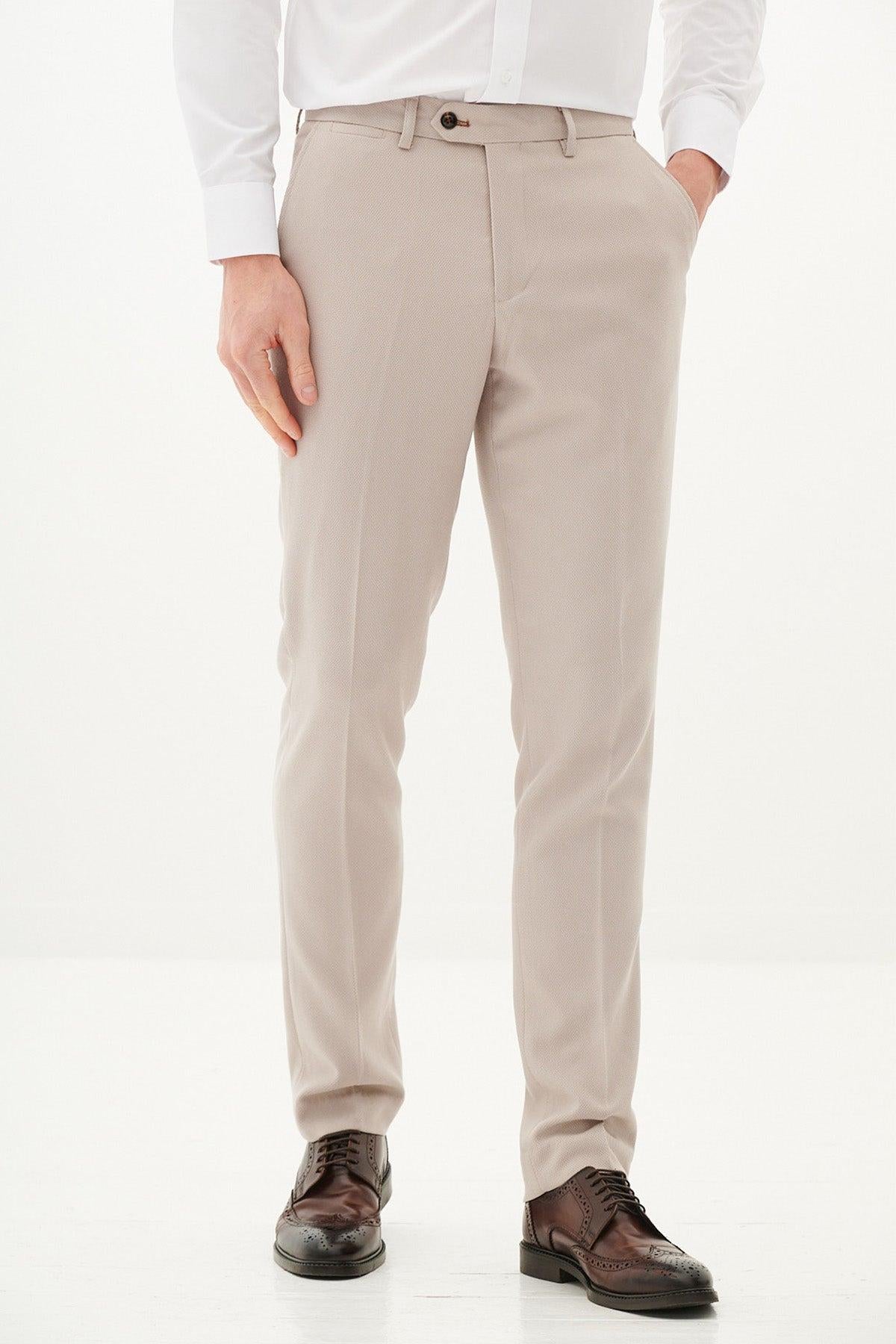A man wears marcdarcy HM5 - Stone Tailored Trousers with brown brogue shoes, his left hand in his pocket for a refined look reminiscent of the Harry Maguire wedding suit style.
