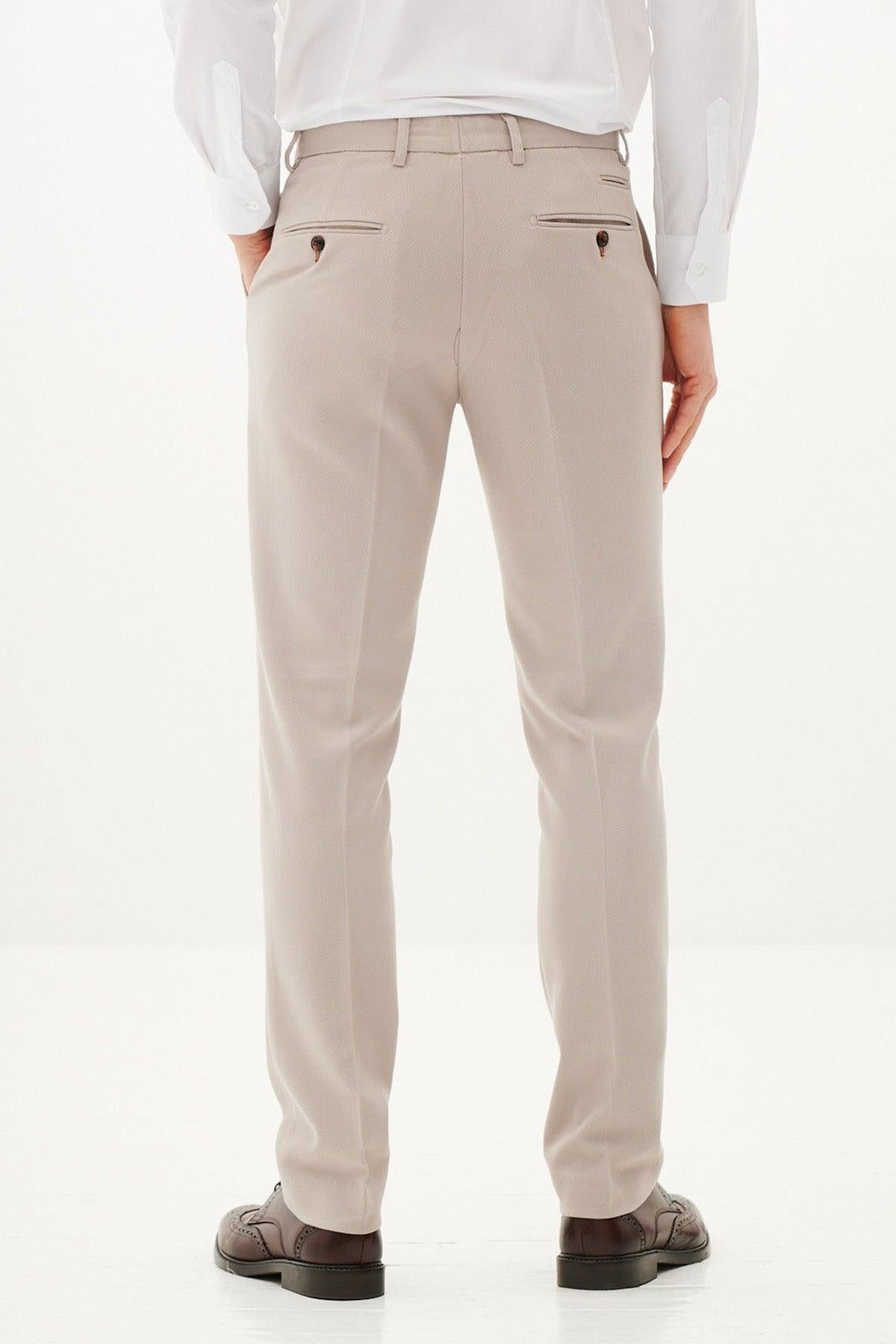 A person wearing marcdarcy HM5 - Stone Tailored Trousers, a white dress shirt, and brown dress shoes stands with their back to the camera against a plain white background.