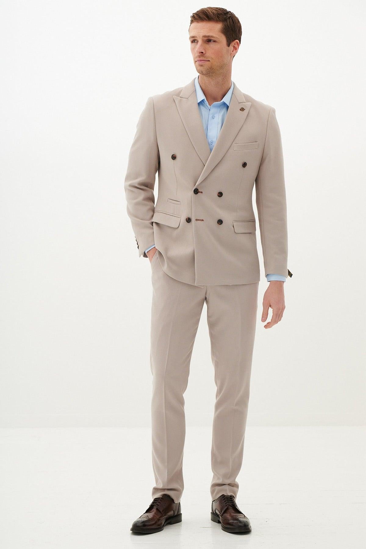 MK Dons footballer Callum Hendry wears a Marc Darcy HM5 Stone double-breasted suit with a light blue shirt and brown dress shoes, standing against a white background facing forward with his left hand in his pocket.