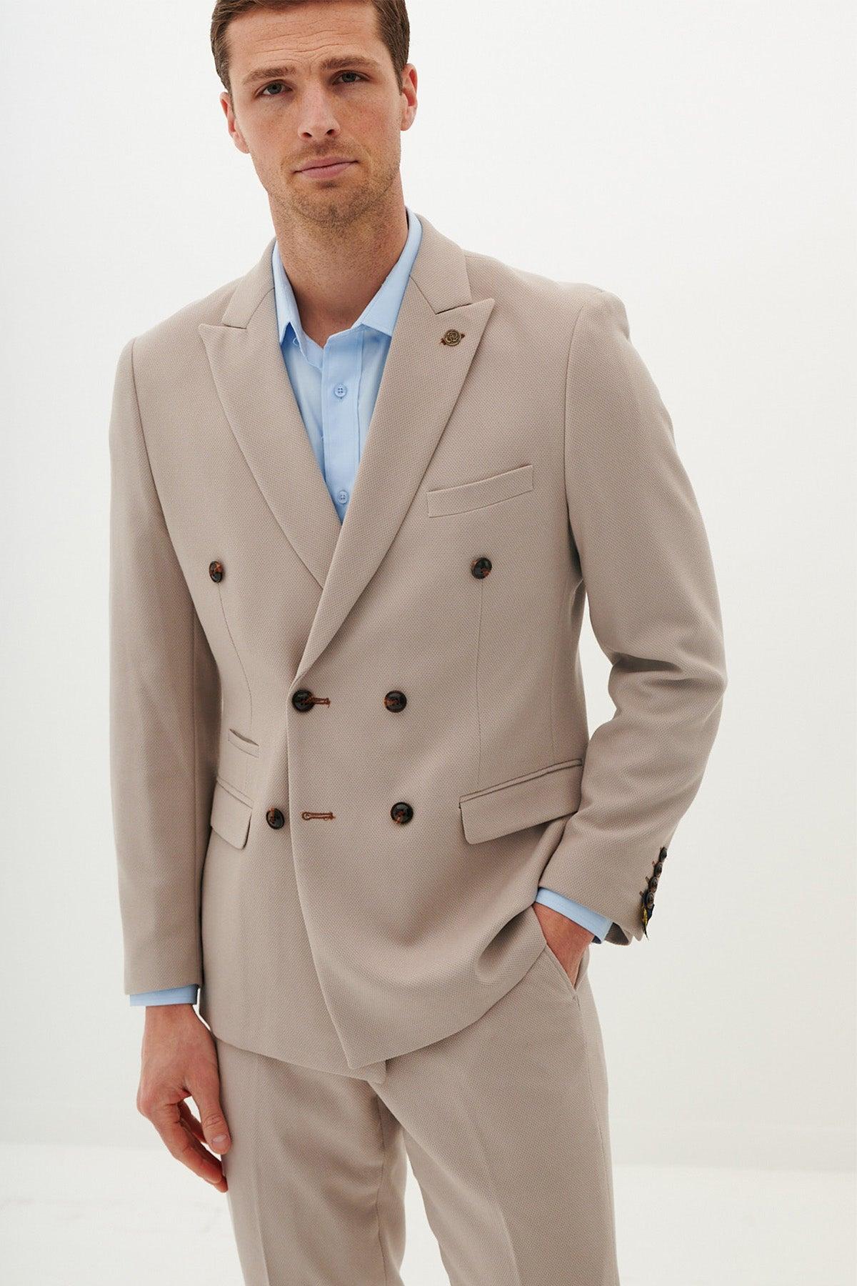 A man wearing the marcdarcy HM5 - Double Breasted Stone Blazer with dark buttons and a light blue shirt stands against a plain white background, looking at the camera with a neutral expression.
