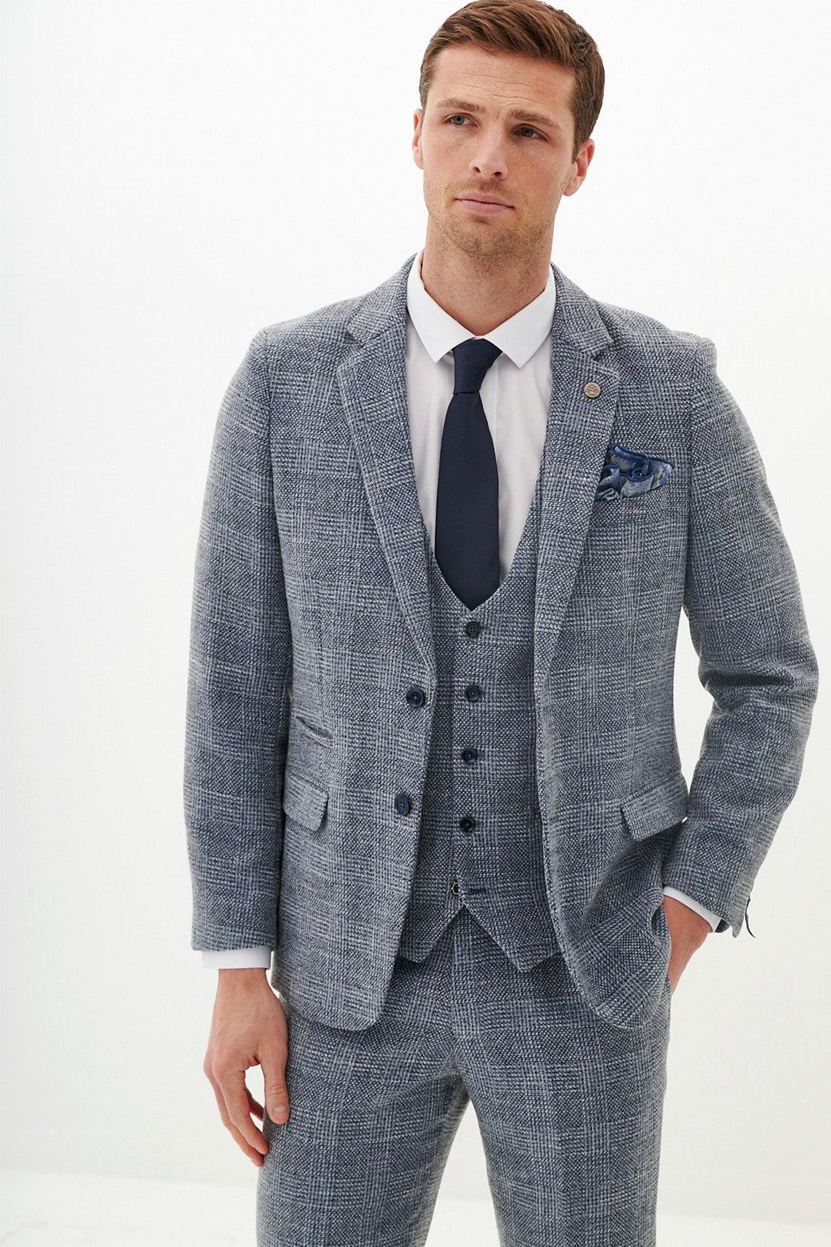 A man wearing the marcdarcy KRIS Sky Blue Tweed Blazer, styled with a white shirt, navy tie, and patterned pocket square.