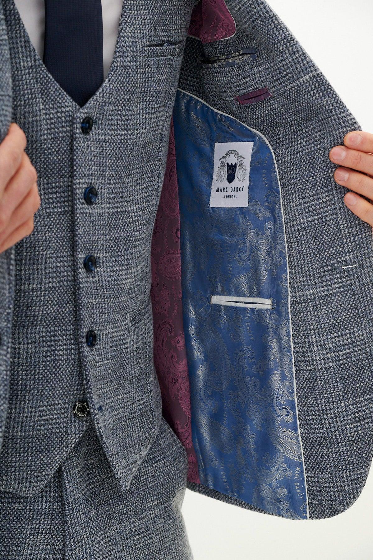 A close-up of a man wearing a marcdarcy KRIS Sky Blue Tweed Suit with a Kelvin Navy Waistcoat, paired with a navy tie and featuring blue paisley lining.