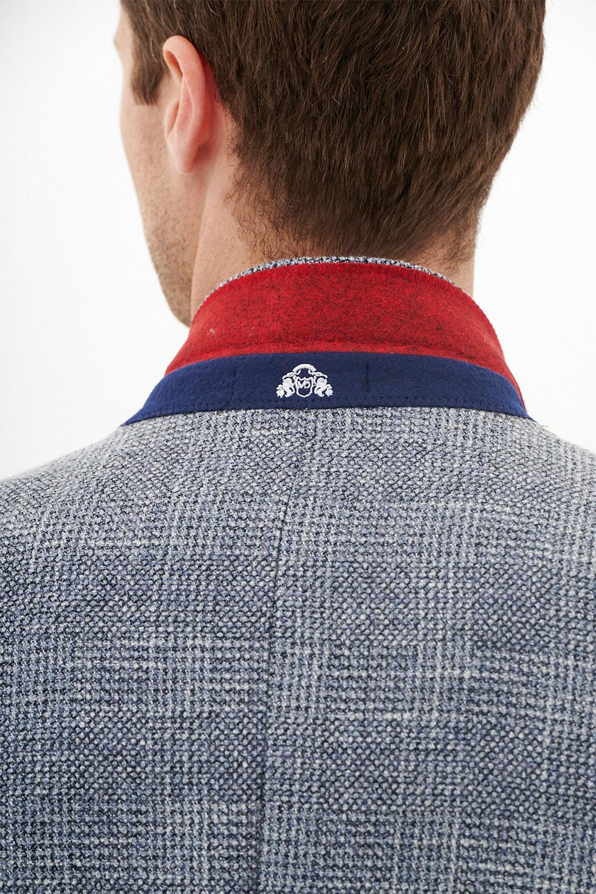 A man is seen from behind wearing the marcdarcy KRIS - Sky Blue Tweed Blazer, featuring a textured check pattern and a blue and red collar with a small white embroidered design on the back of the red collar.