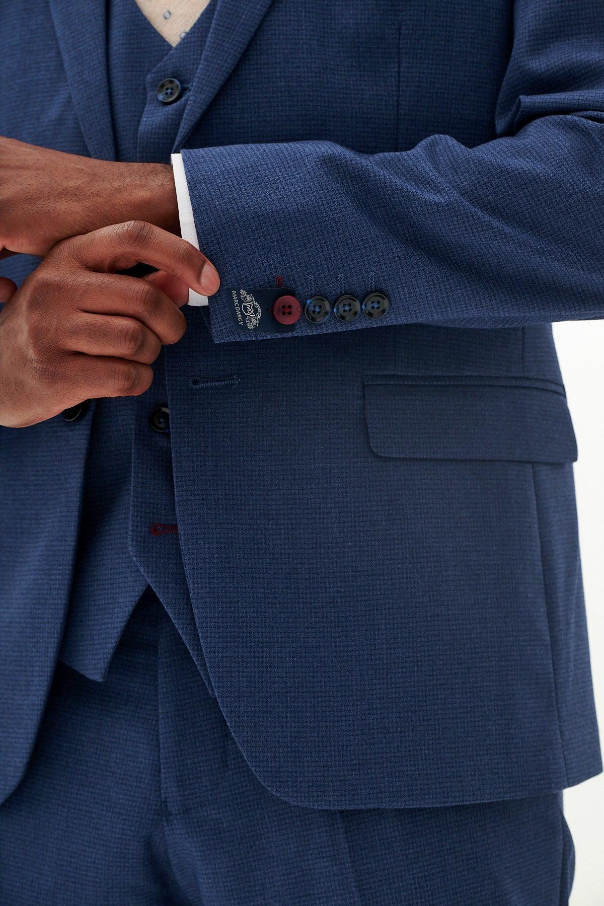 Close-up of a man adjusting his sleeve cuff on the Marc Darcy Official Cardiff City F.C. Club Suit | ASHLEY Navy Blue Three Piece Suit, a slim fit blazer with sleeve buttons—featuring one red accent—and a branded label.