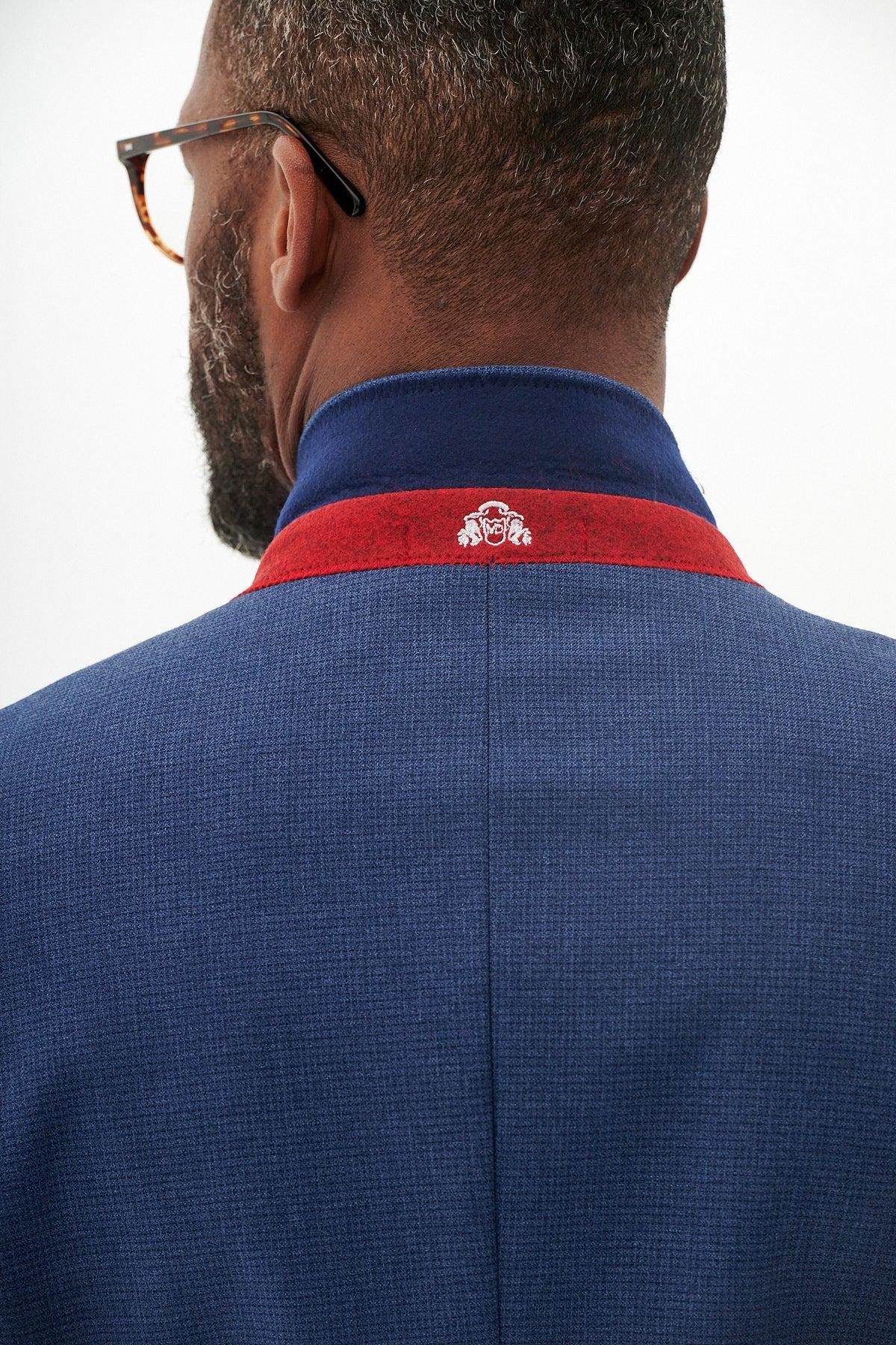 A man's back in the Marc Darcy The Everton Collection | ASHLEY Navy Blue Three Piece Suit, showcasing a red collar accent and a white embroidered crest.