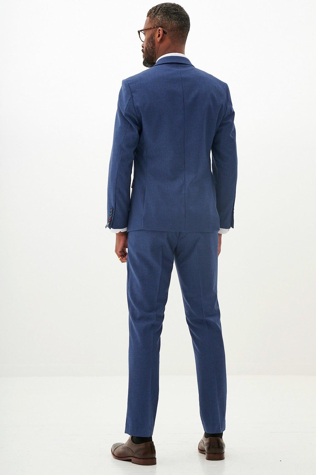 Man in a slim fit Marc Darcy ASHLEY navy blue three piece suit and glasses, seen from the back.