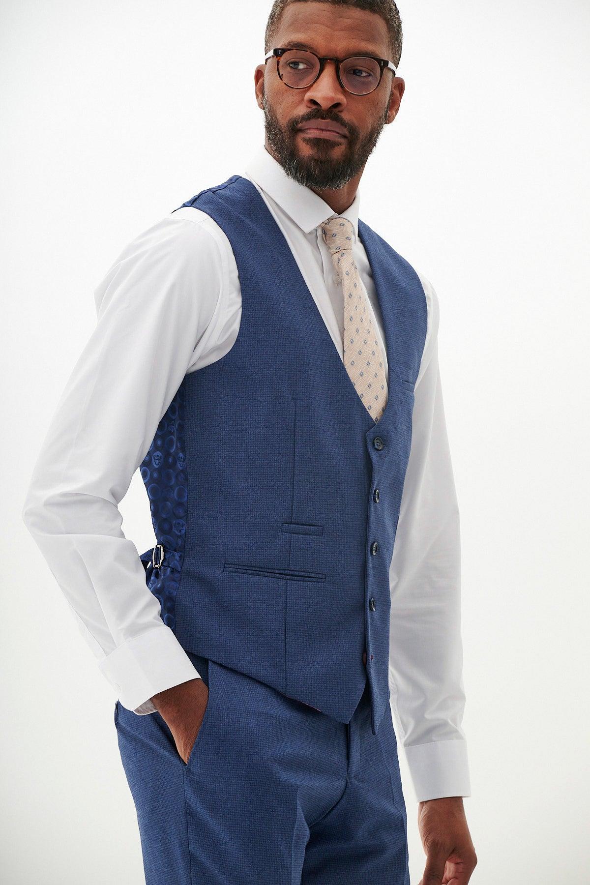 Man wearing the Marc Darcy The Everton Collection | ASHLEY Navy Blue Three Piece Suit, featuring a white dress shirt and patterned tie, with one hand in his pocket.