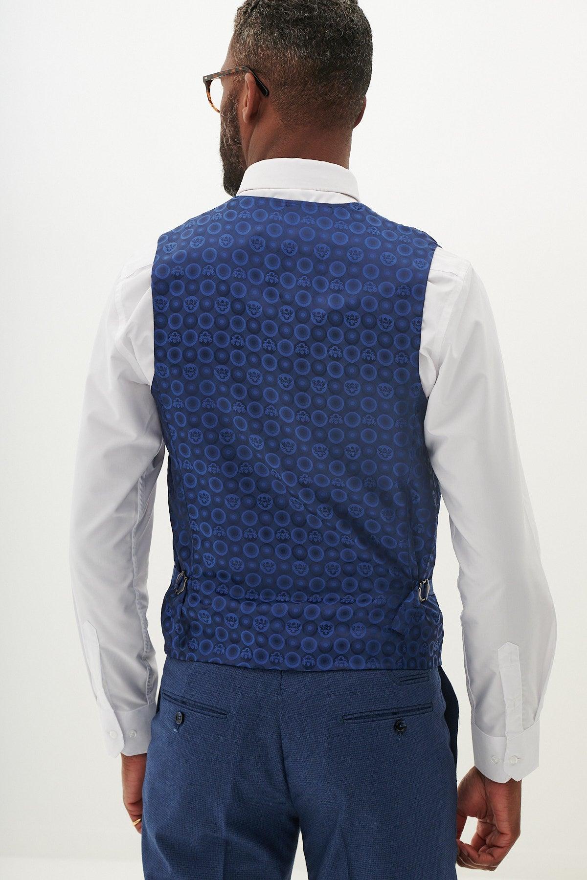 A man is shown from the back wearing Marc Darcy’s WHU Collection - ASHLEY Navy Blue Three Piece Suit as worn by Aaron Wan-Bissaka, featuring a circular-patterned waistcoat and matching blue elastane trousers.