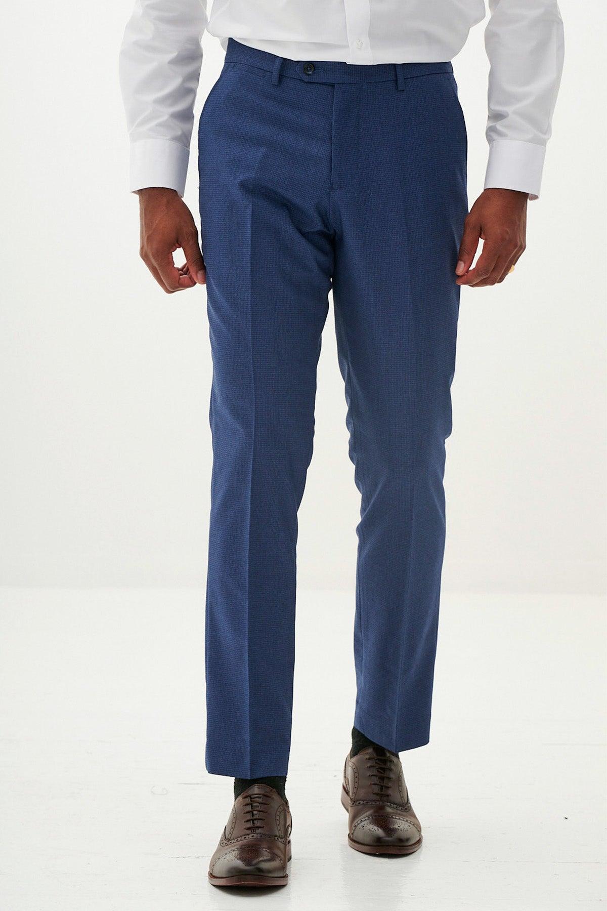 Man in Marc Darcy's WHU Collection - ASHLEY Navy Blue Three Piece Suit as worn by Aaron Wan-Bissaka, paired with a white shirt, dark socks, and brown brogue shoes—a stylish choice for modern formalwear.