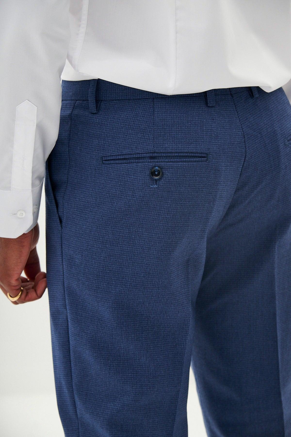 A person wearing The Everton Collection | Tim Iroegbunam in ASHLEY Navy Blue Three Piece Suit by Marc Darcy, shown from the waist down and slightly turned, highlights the refined details and visible back pocket of this slim fit ensemble.