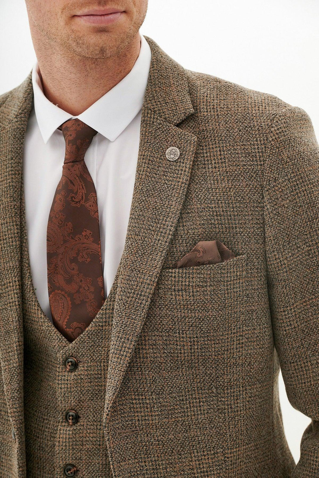 A man wears the marcdarcy KRIS Tan Tweed Three Piece Suit with matching jacket and vest, slim fit white shirt, patterned brown tie, and pocket square. Only his lower face and torso are visible.