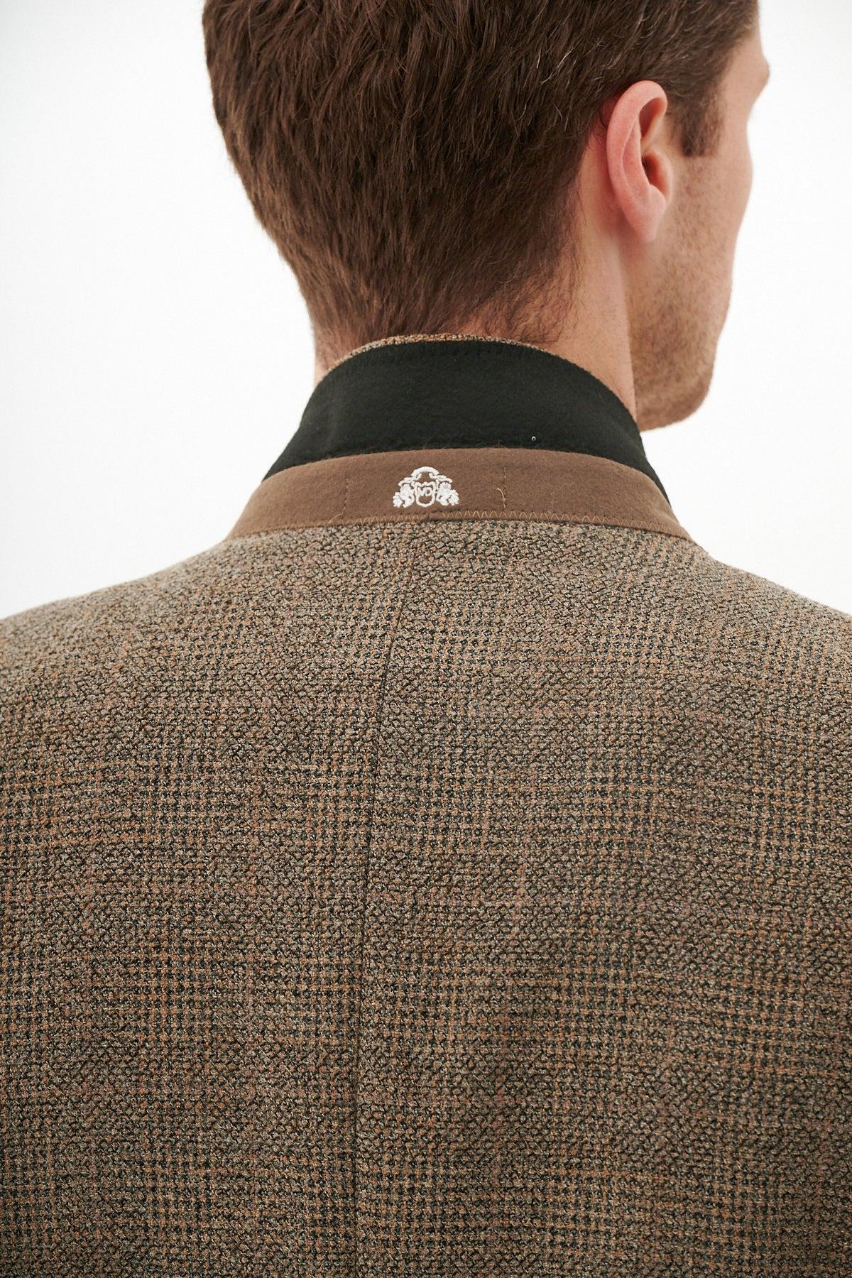 Back view of a man in the marcdarcy KRIS Tan Tweed Three Piece Suit, featuring a slim fit Prince of Wales check and black collar with a detailed white emblem stitched onto it.