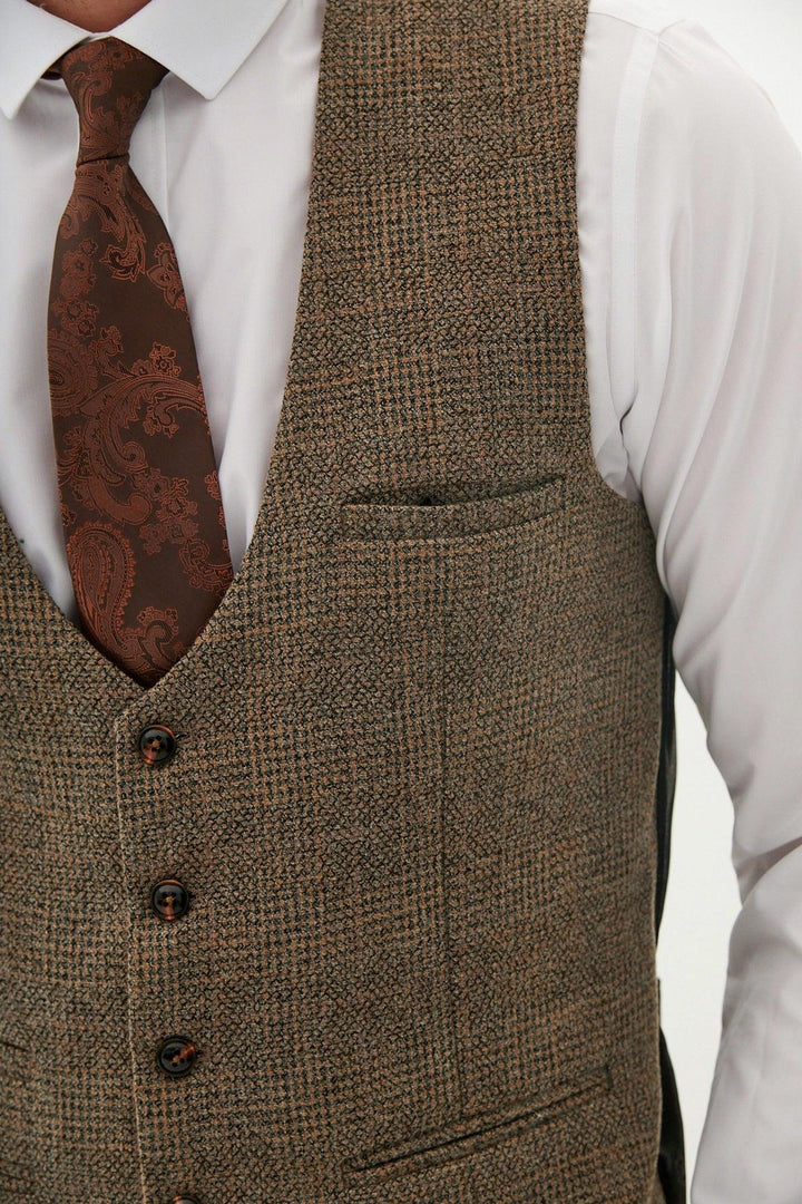 A man wears the KRIS - Tan Tweed Waistcoat by Marc Darcy over a white dress shirt, paired with a brown paisley tie. The image focuses on his torso, not showing his face.