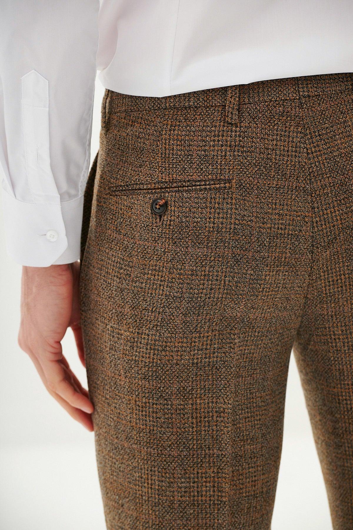 Close-up of a person wearing the marcdarcy West Bromwich Albion F.C. Collection | KRIS Tan Tweed Suit pants, as seen on Jayson Molumby, featuring a Prince of Wales check pattern, buttoned back pocket, and paired with a white long-sleeve shirt.