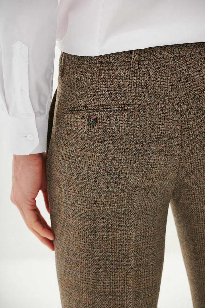A close-up of a person wearing the marcdarcy KRIS Tan Tweed Three Piece Suit, highlighting the back pocket detail of the trousers and part of their white dress shirt, with their arm and hand visible.