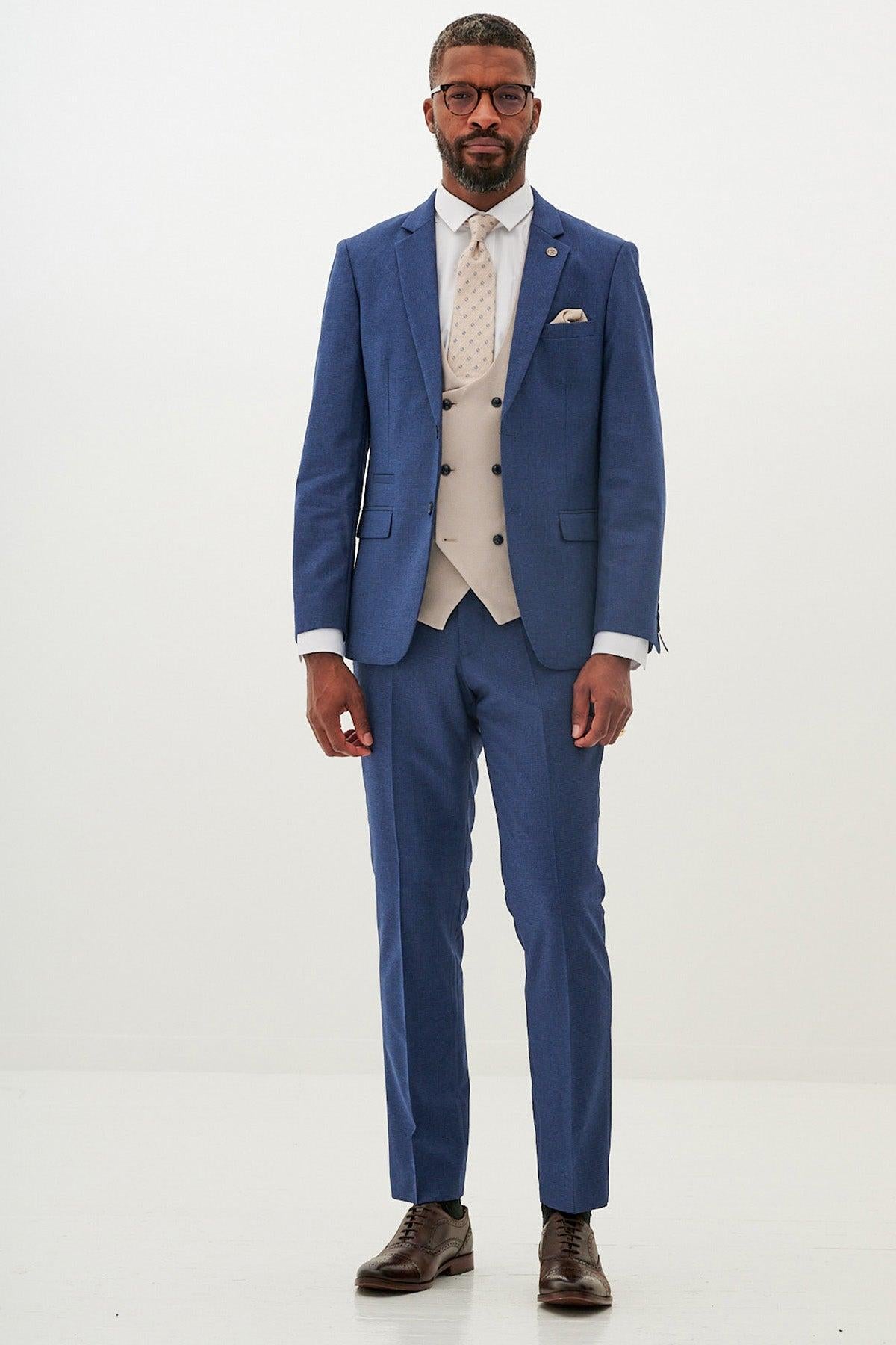 A man stands against a plain white background wearing the Marc Darcy ASHLEY navy blue suit with a Kelvin Stone waistcoat.