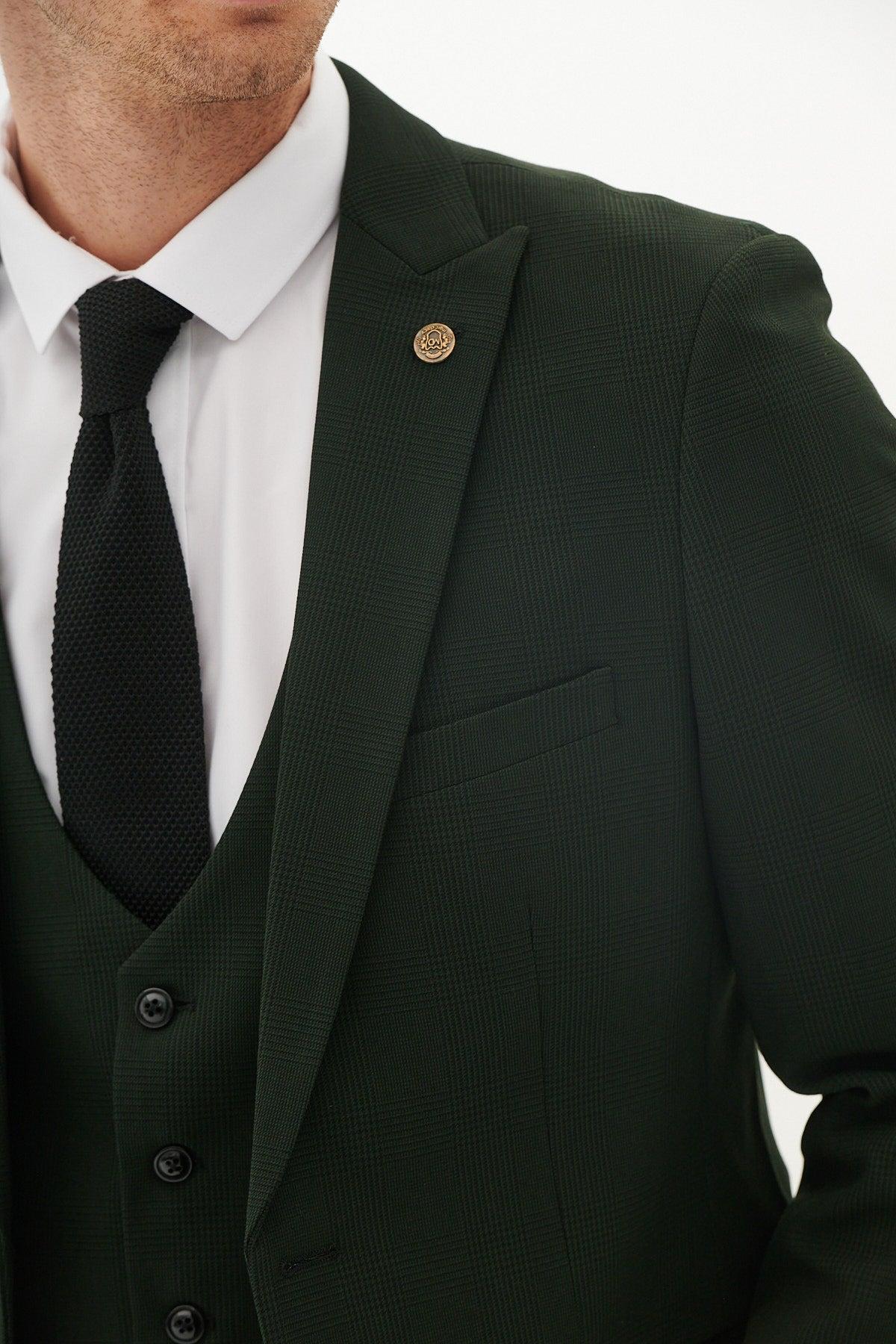 A man wears the Marc Darcy BROMLEY - Olive Green Check Blazer with a white shirt, black tie, and finishes his look with a gold lapel pin.