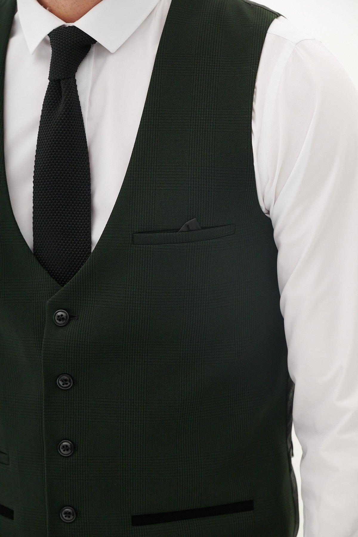 A man wears the Marc Darcy "The Cardiff City F.C. Collection - BROMLEY" olive green check suit, as worn by Karlan Grant, featuring black buttons and a pocket with a dark handkerchief over a white shirt and black tie.
