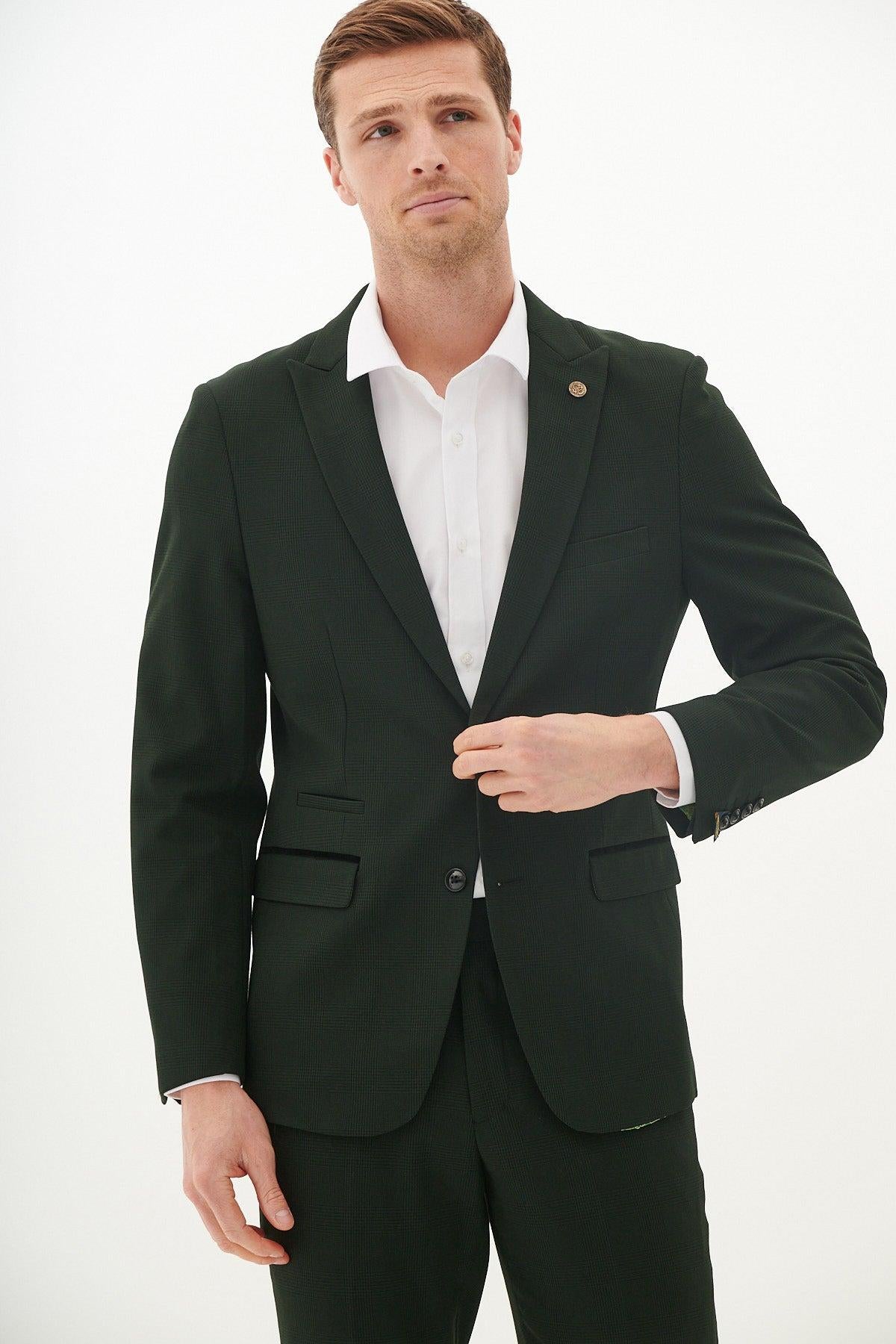 Alex Robertson models the Marc Darcy BROMLEY Olive Green Check Blazer from The Cardiff City F.C. Collection, standing against a white background and adjusting his jacket while looking slightly upward.