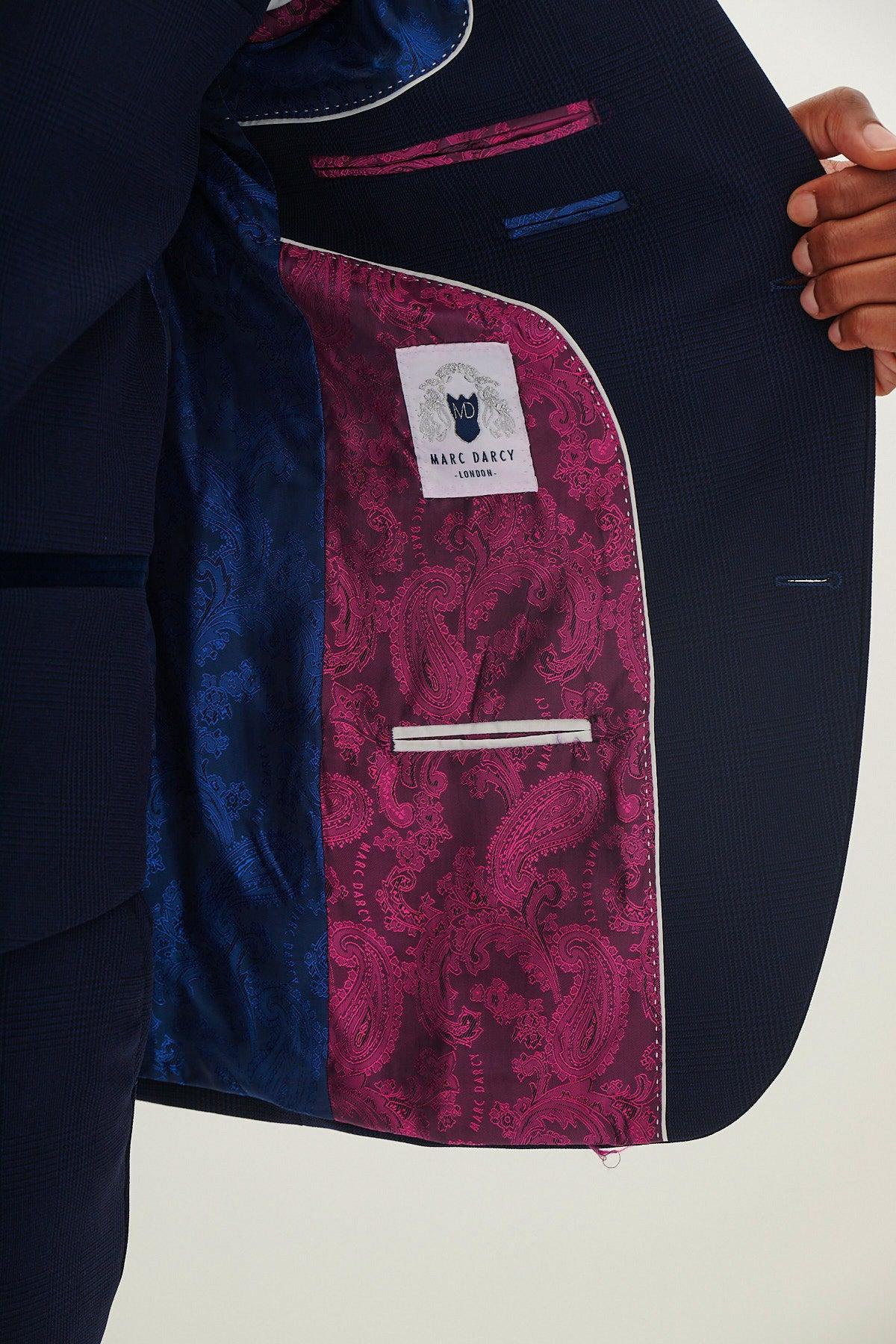 A person holds open the BROMLEY - Navy Check Blazer by Marc Darcy, revealing its vibrant blue and pink paisley inner lining and visible white Marc Darcy label—an eye-catching detail in modern formalwear.