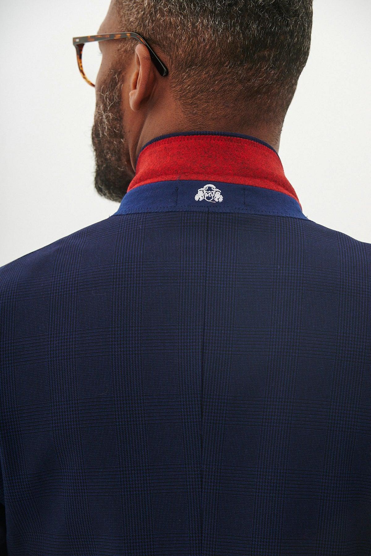 A man seen from behind wearing glasses and the Marc Darcy BROMLEY - Navy Check Blazer, a slim fit jacket with a red collar and small white embroidered logo on the back.
