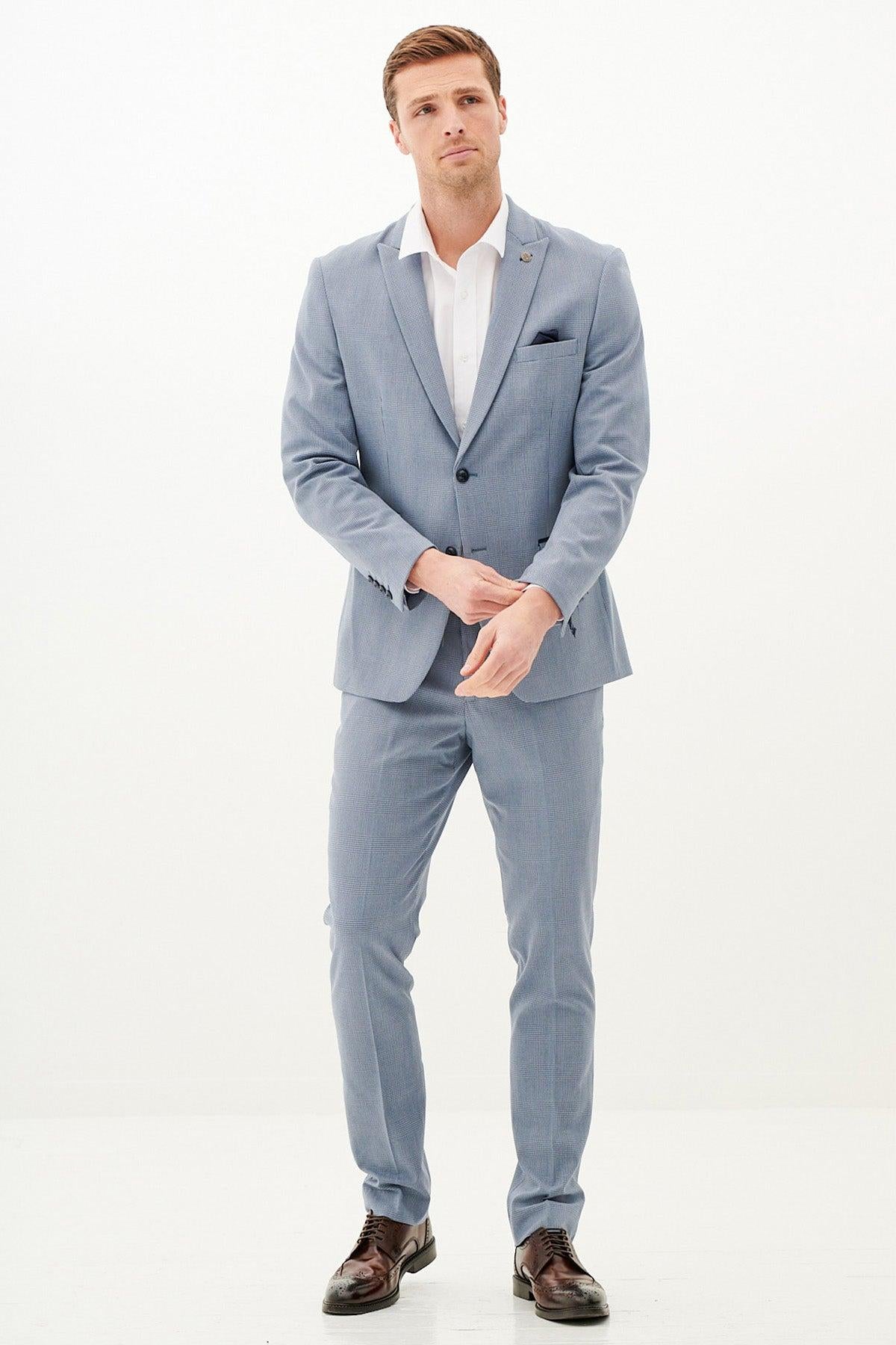 A man wears the Marc Darcy BROMLEY - Sky Blue Check Blazer, featuring a slim fit and styled with a white shirt and dark pocket square, as he looks away from the camera.