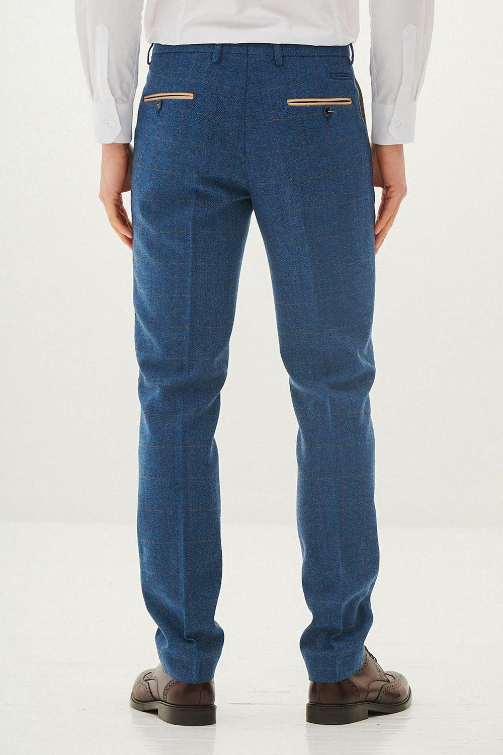 A person in a white shirt and marcdarcys DION - Blue Tweed Check Trousers stands facing away. The trousers are tailored with two button-closure back pockets, while brown dress shoes complete the look against a plain white background.