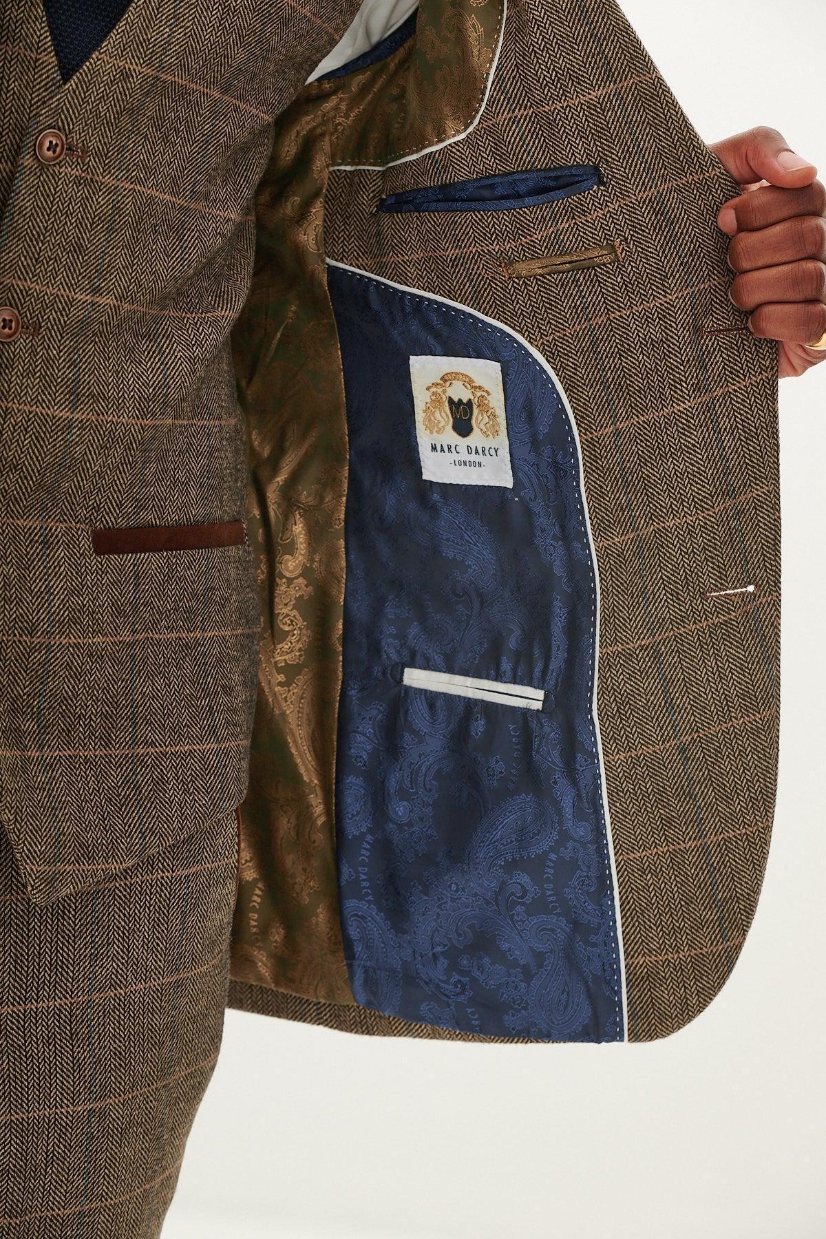 A person opens the inside of a tan tweed check blazer from marcdarcy, showing off its stylish brown and blue patterned lining, multiple inner pockets, and signature label—ideal details for an elegant country wedding look.
