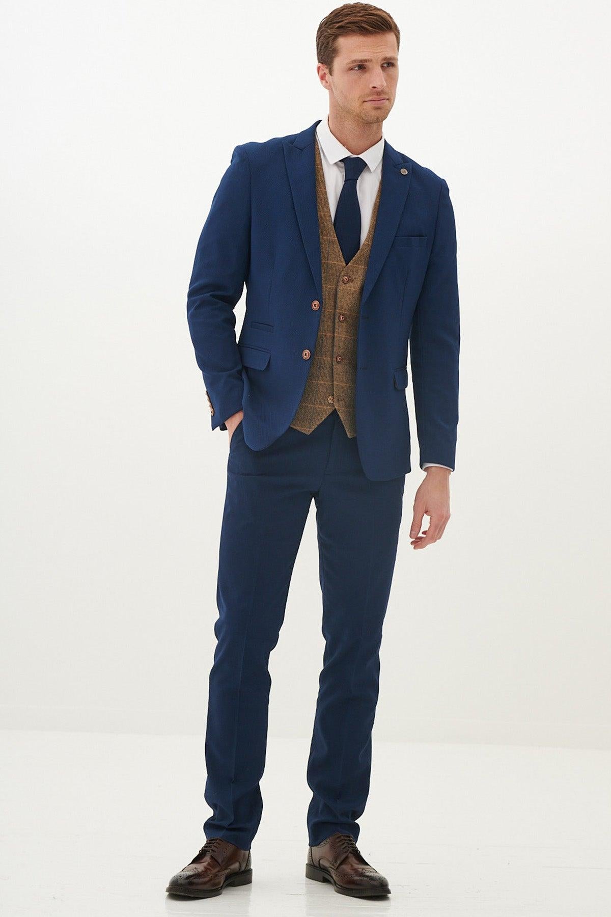 A man with short brown hair and a neutral expression wears the marcdarcy MAX - Royal Blue Suit With Kris Tan Tweed Suit, paired with a slim fit blazer, white shirt, dark blue tie, and brown dress shoes against a plain white background.