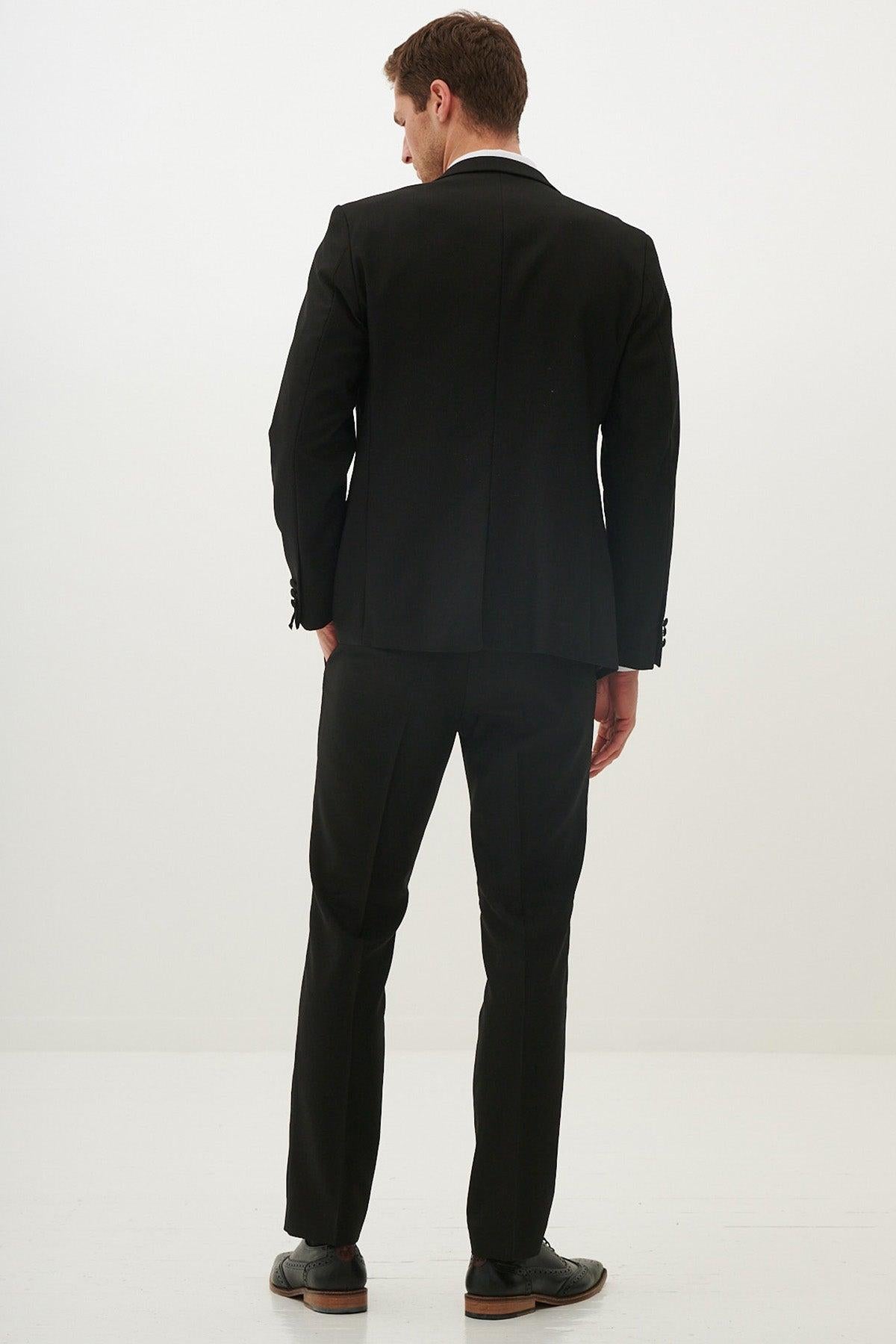 A man stands from behind in a marcdarcy Matching Father & Son | DALTON Black Tux Three Piece Suit, looking down with hands in pockets.