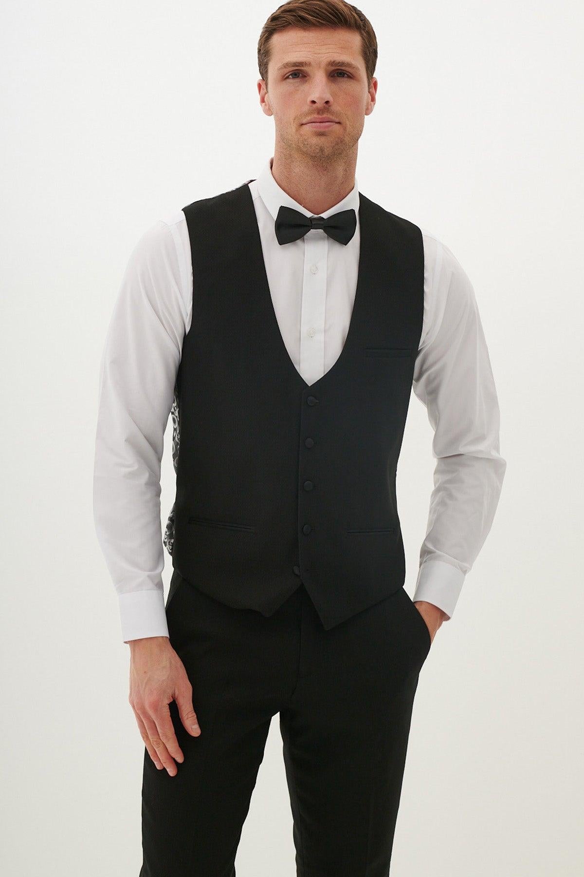 A man in a slim fit white dress shirt, black bow tie, marcdarcy DALTON - Black Diamond Waistcoat, and black trousers poses against a white background—a sharp look ideal for black tie events.