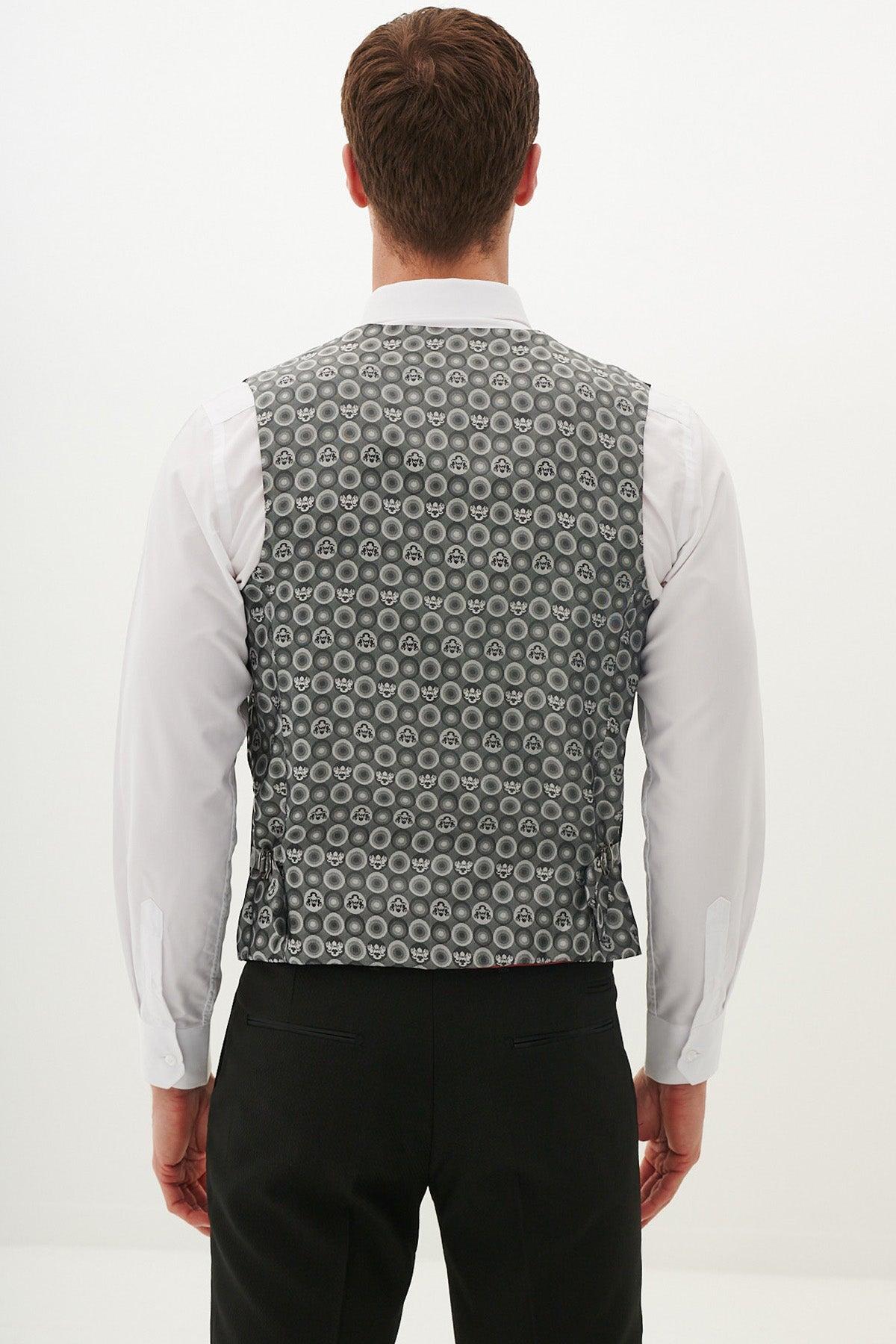 A man stands facing away in the marcdarcy Matching Father & Son | DALTON Black Tux Three Piece Suit, featuring a white shirt, black pants, and a gray patterned vest with circles. The background is plain white.