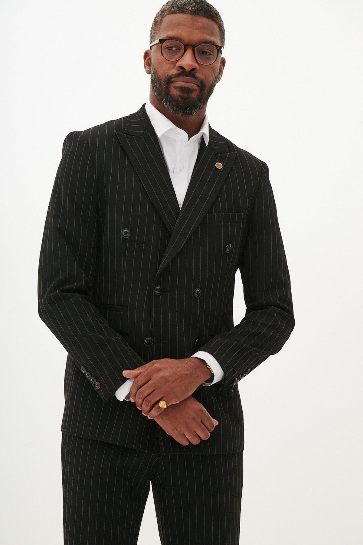 A Black man wears the Marc Darcy ROCCO black pinstripe double-breasted blazer, paired with a white shirt, glasses, and a gold ring.
