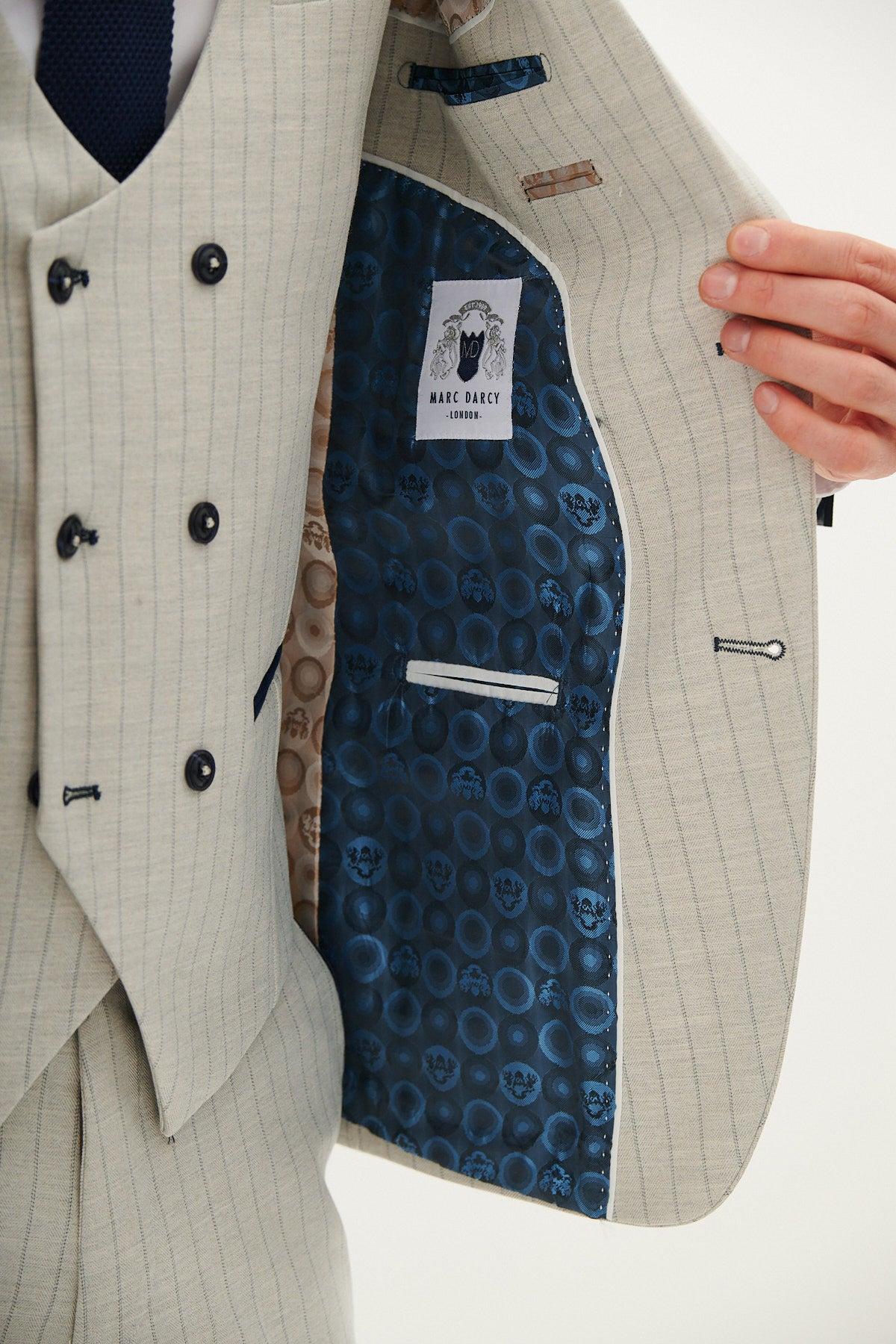 A person in the GRANT - Stone Pinstripe Double Breasted Suit by Marc Darcy opens the jacket, showing a blue patterned lining with a Marc Darcy label, contrasting fabric accents, and an interior pocket.