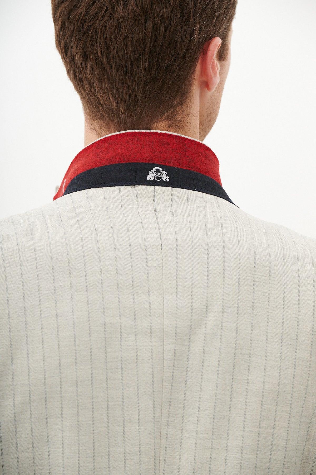 Close-up of the back of a man's head and shoulders, wearing the Marc Darcy GRANT - Stone Pinstripe Blazer featuring a red and navy collar and a small embroidered logo.