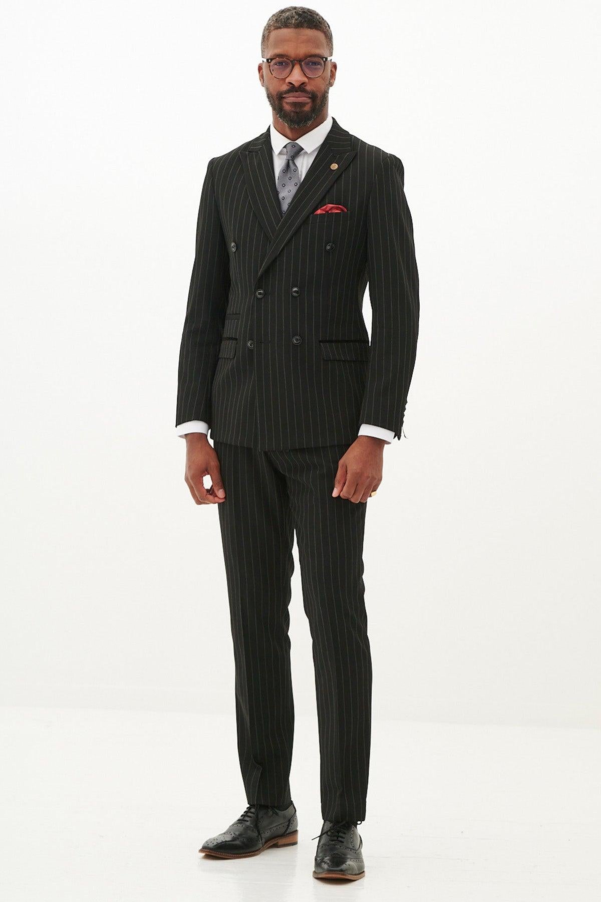 A man wearing the Marc Darcy ROCCO black pinstripe double-breasted two-piece suit, white shirt, patterned tie, red pocket square, and black dress shoes stands against a plain white background. He has eyeglasses and a beard.