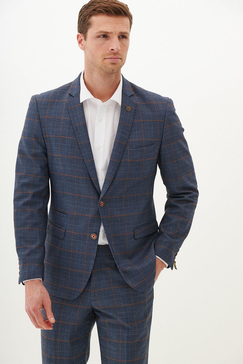 A man wearing the marcdarcy JENSON Sky Blue Check Blazer with a white dress shirt stands against a white background, looking slightly to the side with one hand in his pocket.