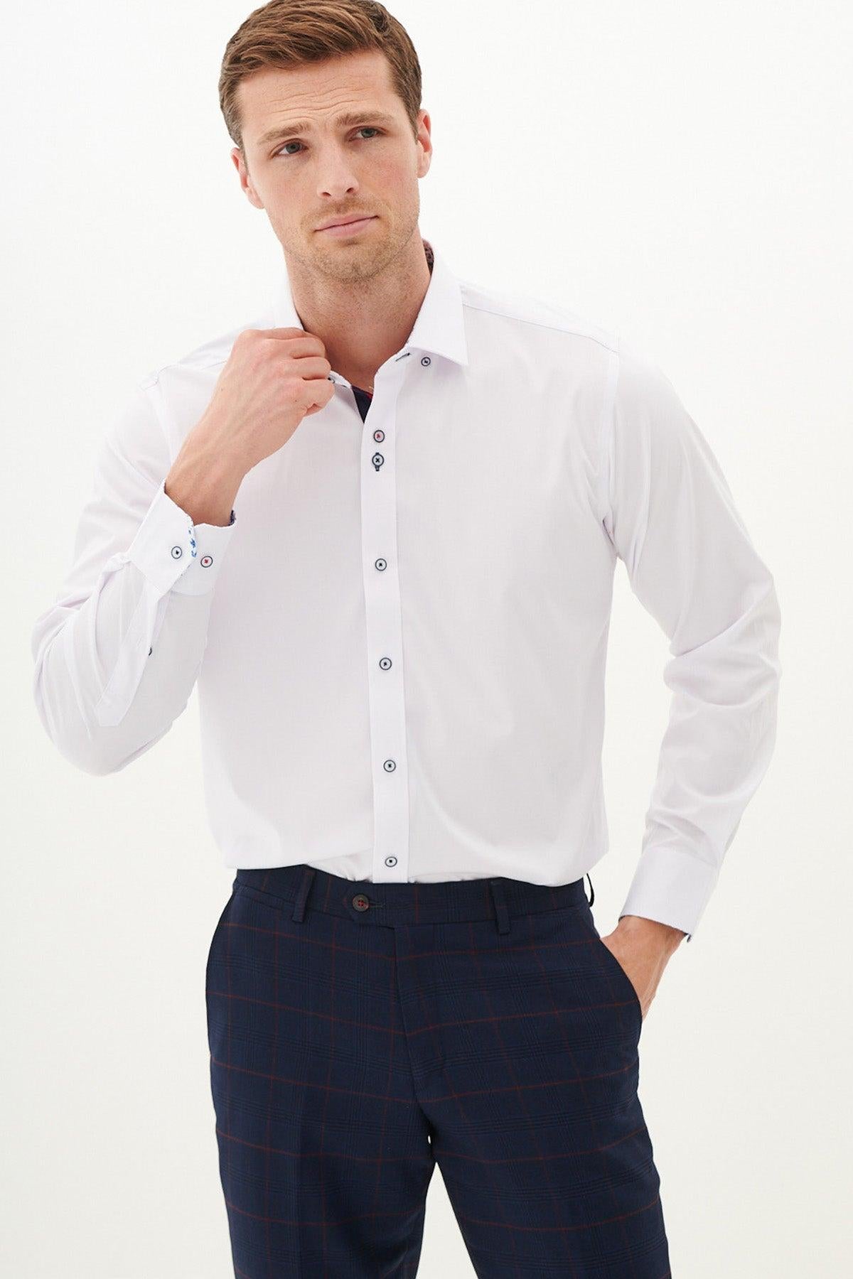 A man wearing the Marc Darcy LUKE White Long Sleeve Shirt and dark plaid trousers stands against a plain light background, adjusting his collar while looking slightly to the side.