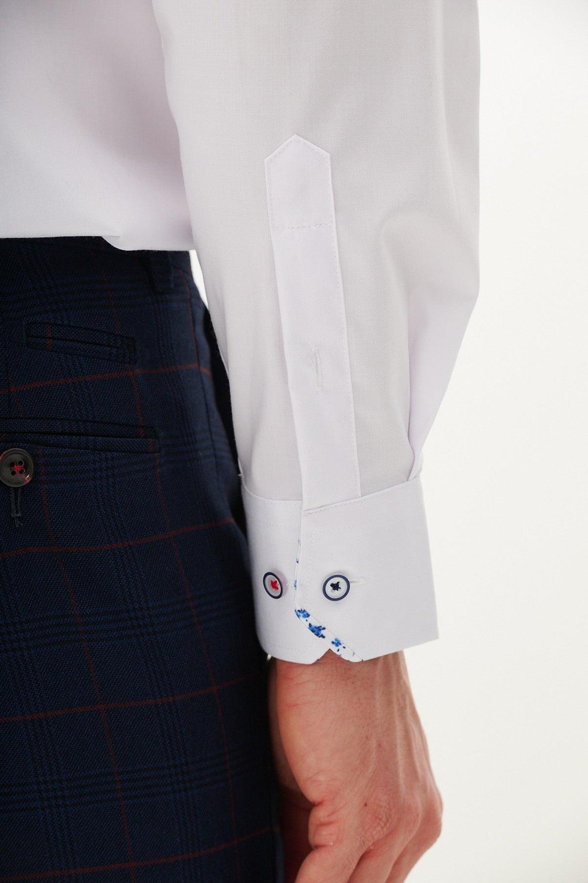 A person wears the Marc Darcy LUKE white long sleeve shirt with subtle floral detail and blue/red cuff buttons, paired with dark blue plaid pants featuring red lines. Only their lower arm and part of the torso are visible.