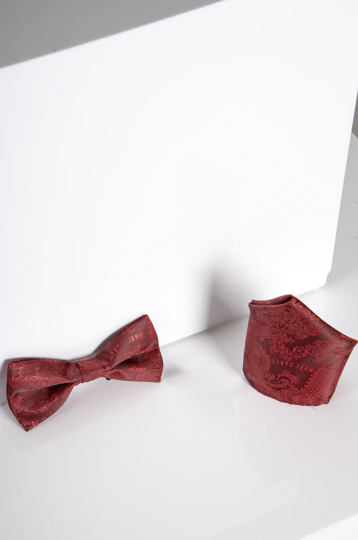 The MD PAISLEY - Wine Paisley Bow Tie and Pocket Square Set by Accessory is displayed on a white surface, ideal for evening wear, featuring subtle shadows against a clean white background.