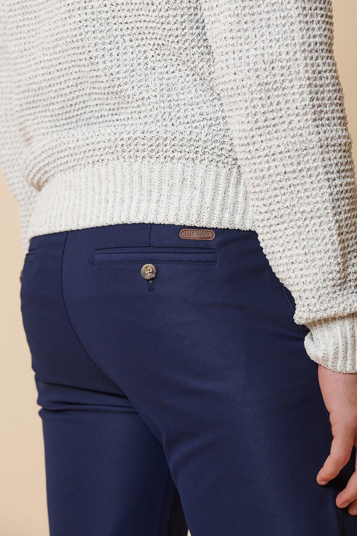 A person is seen from the back waist down wearing a white textured knit sweater and marcdarcy's ENZO Royal Blue Chinos, which feature a buttoned back pocket and a small brown leather patch above it.
