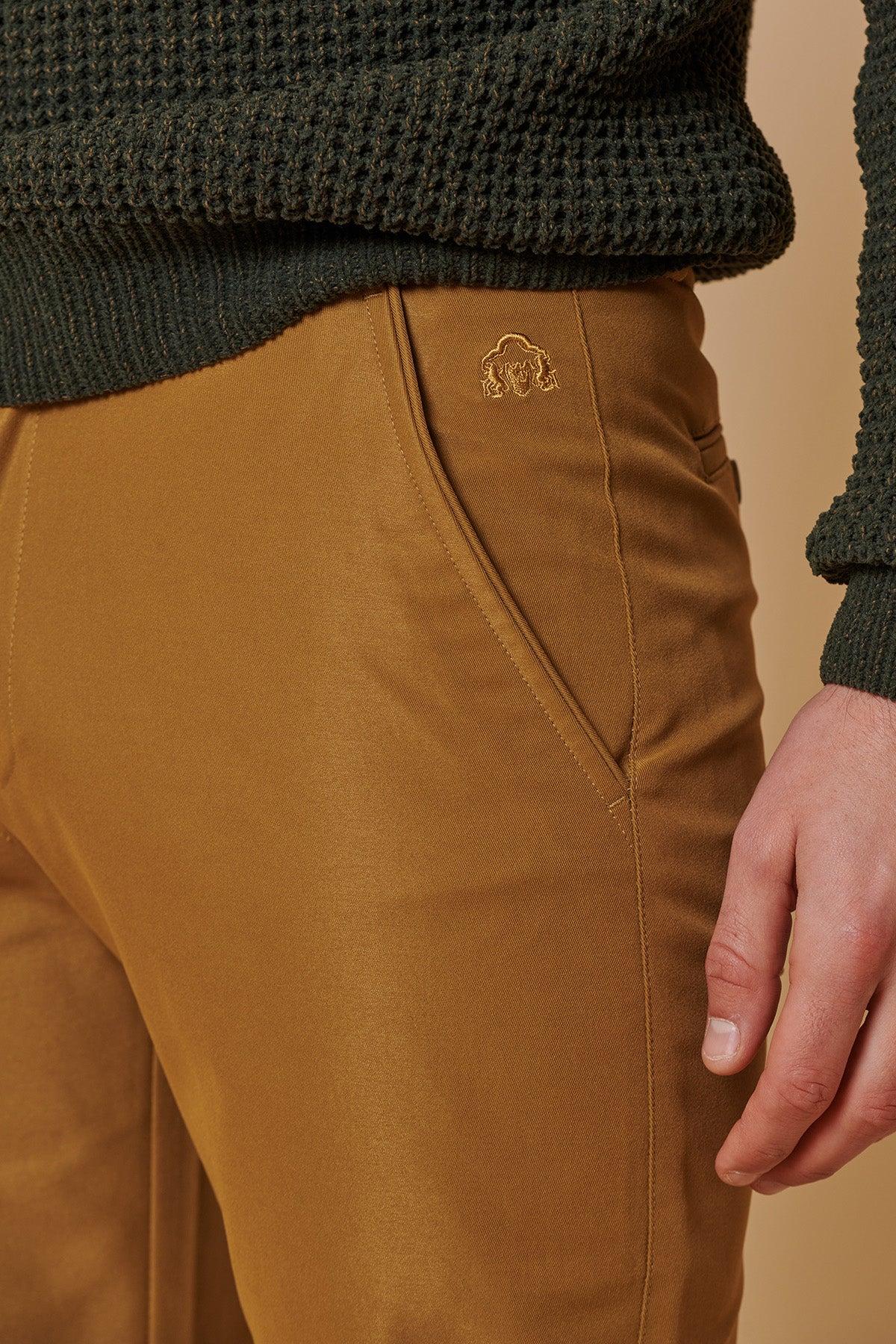 Close-up of marcdarcy ENZO - Tan Chinos, featuring a gold embroidered bull logo on the pocket, paired with a dark green sweater.