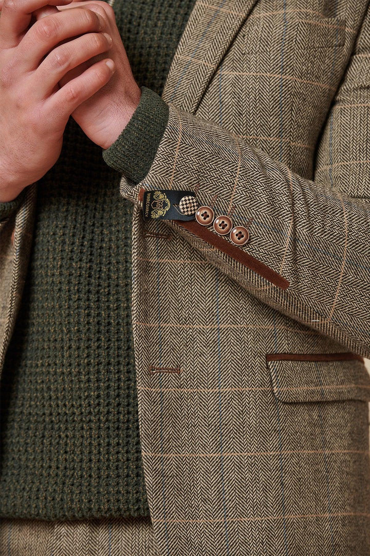 Wearing the Marc Darcy TED Tan Tweed Check Two Piece Suit, styled with a green textured sweater, the clasped hands by the lapel echo classic Peaky Blinders style and a refined heritage vibe.