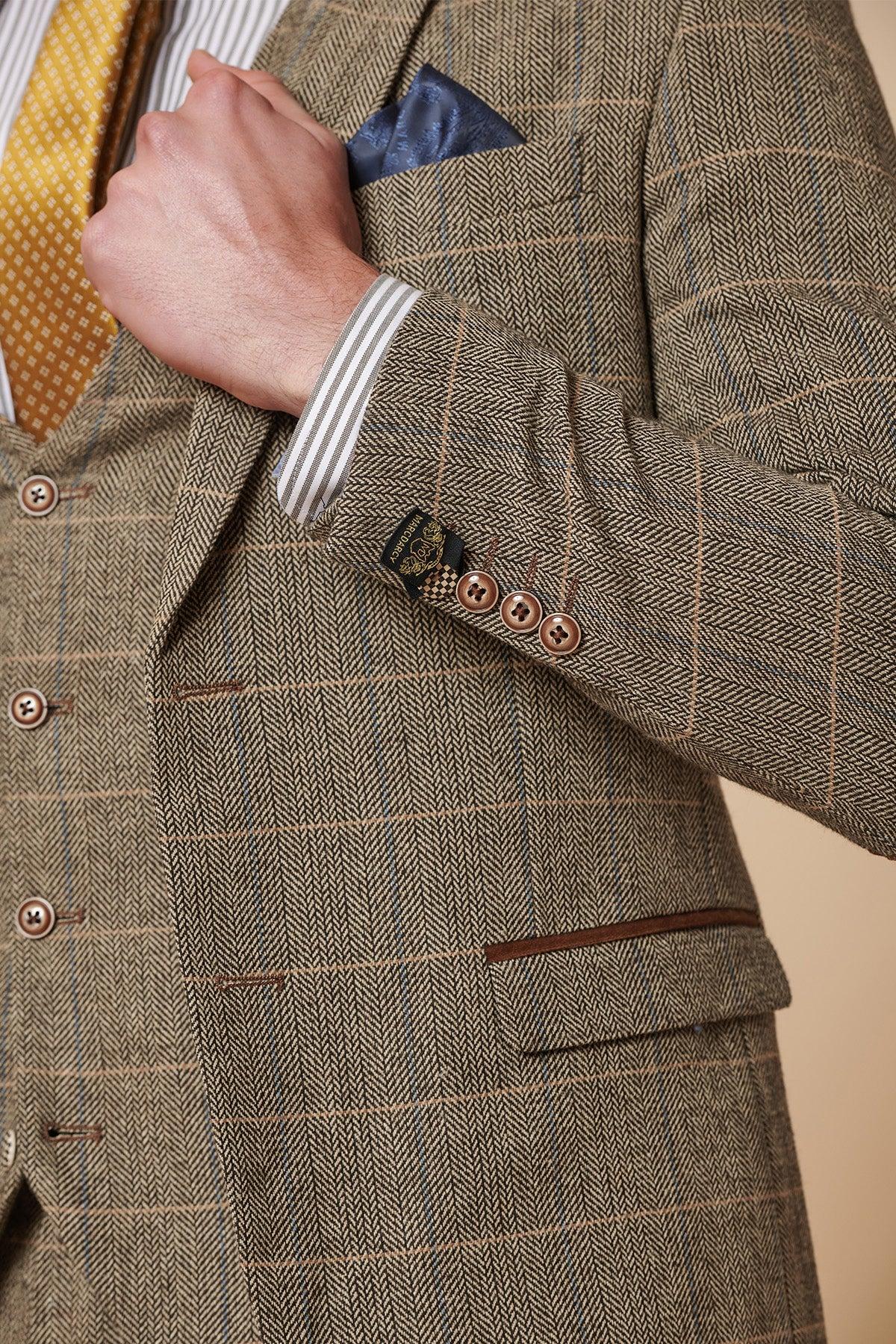 Close-up of a person wearing the marcdarcy DX7 - Tan Tweed Check Two Piece Suit, styled with a yellow patterned tie, striped shirt, and blue pocket square. Features include detailed sleeve and pocket stitching and buttons.