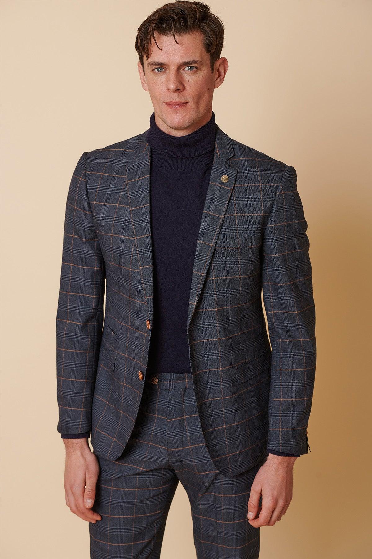 A man stands against a beige background, wearing the Marc Darcy JENSON - Marine Navy Check Two Piece Suit and a dark blue turtleneck, looking at the camera with a neutral expression.