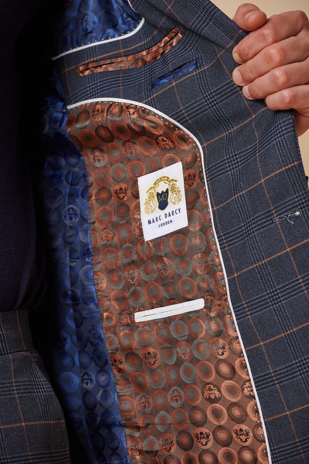 A person holds open a JENSON - Marine Navy Check Two Piece Suit jacket by Marc Darcy, revealing an ornate brown patterned lining with a Marc Darcy label sewn inside.